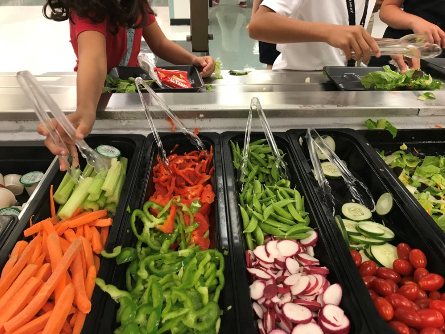 students filling their tray with fruit and veggies